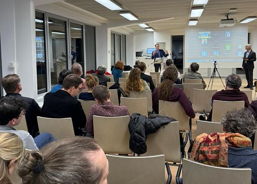 Eine Gruppe von Leuten hören einer Keynote zu.